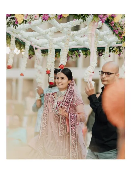 The bride's beautiful entrance under a traditional phoolon ki chadar, a moment of grace and anticipation.