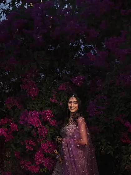A beautiful portrait of the bride against a backdrop of purple bougainvillea at twilight. The soft light and vibrant colors create a romantic and dreamy atmosphere.