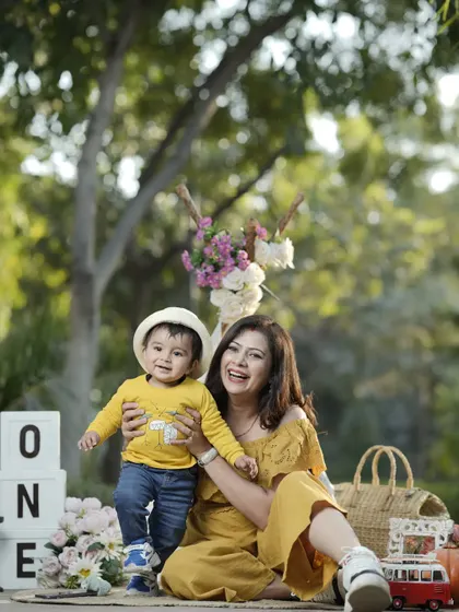 A mother's joy is her child's smile. A candid moment from a first birthday picnic, filled with laughter and love.