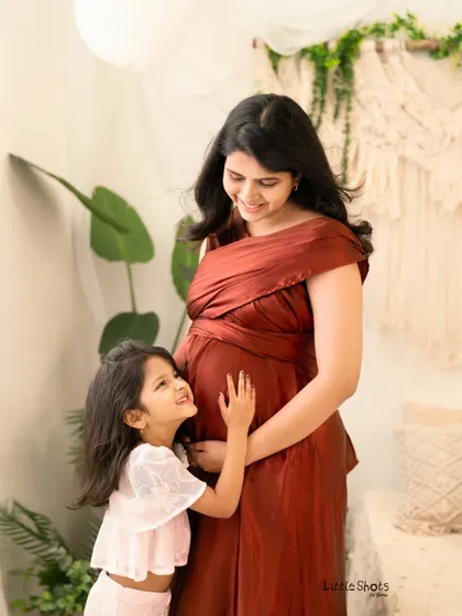 A daughter looks up with adoration at her mother's baby bump. This candid shot captures the pure and simple love of a child excited for her new sibling.