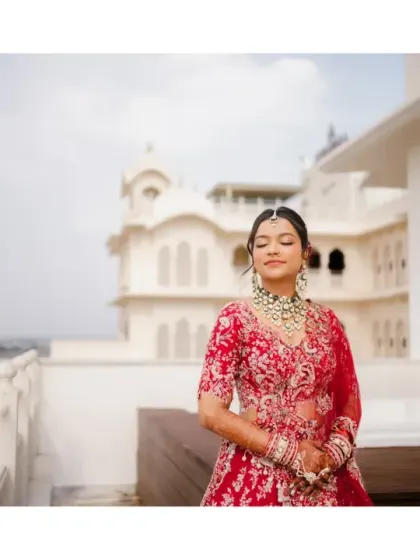 The bride, in her magnificent red lehenga, soaks in the moment on a palace rooftop. Her serene expression and the beautiful backdrop create a breathtaking bridal portrait.