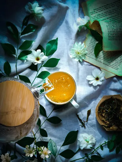 A moody, artistic shot of tea being poured, with dramatic lighting and natural elements creating a serene, contemplative scene.