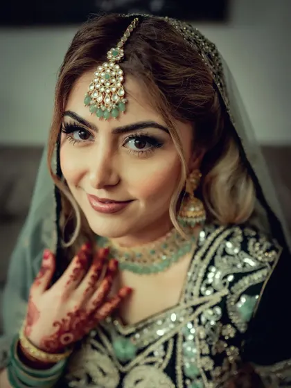 A close-up portrait of a bride with stunning makeup and jewelry, her happy expression shining through.