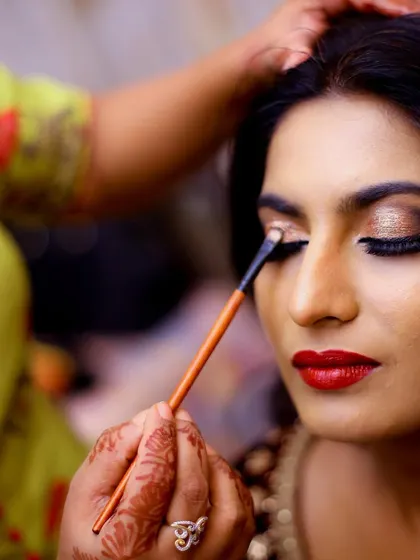 A make-up artist applies eyeshadow to the bride. We capture these behind-the-scenes moments to tell the complete story of your transformation.