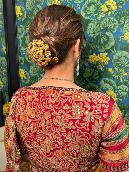 A close-up of this classic saree look. The hair is styled in an elegant bun with a beautiful accessory, and the makeup is soft and timeless.