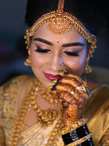 A candid moment of the bride, her eyes closed in a smile, showing off her beautiful makeup and the dark henna on her fingers.