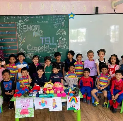 A class poses with their teachers and the items they presented during the 'Show and Tell' competition, celebrating a day of creative expression.