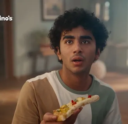 This shot captures the moment a character takes his first bite of pizza. His surprised and delighted expression is the focal point, supported by his casual, everyday styling.
