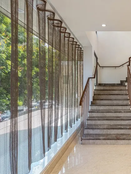 An undulating mesh curtain was introduced along the glass facade of the Nalli store. This element controls the intense glare of the Chennai sun while adding a layer of translucency and texture to both the interior and exterior.