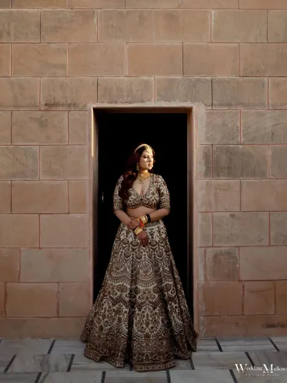 A powerful bridal portrait of Urjaa. The contrast between the light from the doorway and the stone wall creates a dramatic, regal effect.