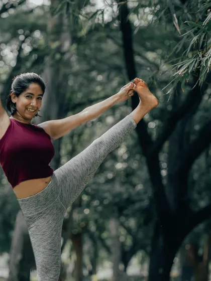 A joyful Utthita Hasta Padangusthasana, or Extended Hand-to-Big-Toe Pose, in the park. This posture is a fantastic way to challenge your balance while stretching your hamstrings.