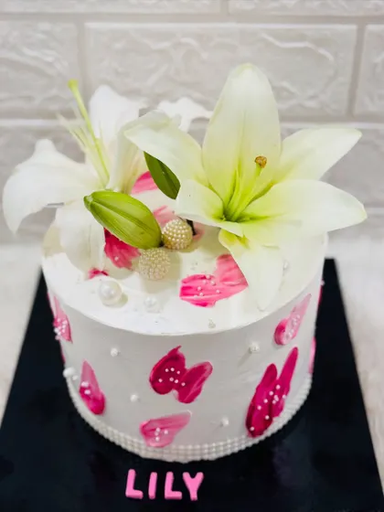 A simple and stunning cake named "Lily," adorned with fresh white lilies and abstract pink brushstrokes for an artistic touch.