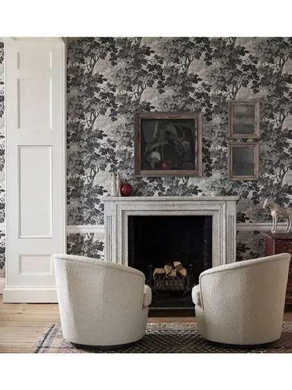 The 'Richmond Park' wallpaper in a charcoal colourway brings a classic, pastoral feel to this living room. Paired with a marble fireplace and modern chairs, it bridges the gap between traditional and contemporary style.