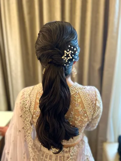 A chic and playful ponytail with a twist. The style is adorned with a beautiful star-shaped pearl accessory, perfect for a sangeet or reception.