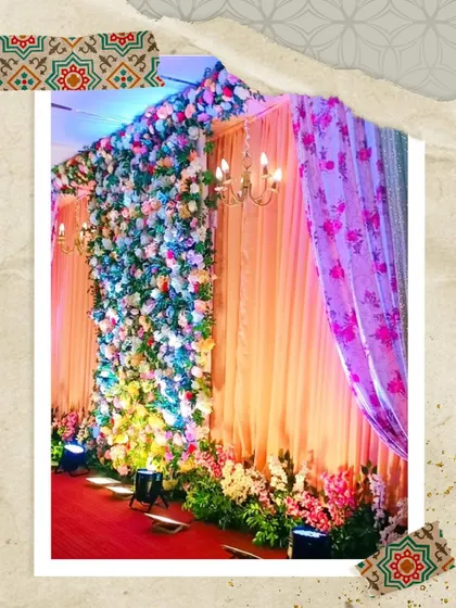A stunning photo backdrop combining a dense floral wall with dramatic uplighting. The lights add depth and texture to the flowers, making it a perfect spot for beautiful pictures.