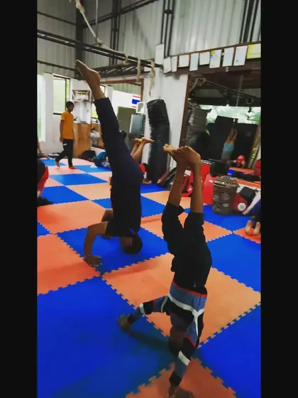 Two students practicing their handstands side-by-side. This helps them work on their form and endurance for holding the pose longer.