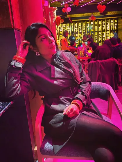 A moody, stylish shot from a night out. The trench coat and all-black base layer create a chic and mysterious vibe, perfect for an evening at a lounge.