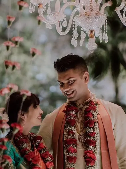 A romantic close-up of a couple under a chandelier, sharing a sweet moment during their wedding ceremony.