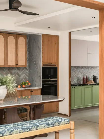 This view shows the seamless flow from the dining area into the kitchen, where warm oak cabinetry meets cool grey tiles and fresh green base units.