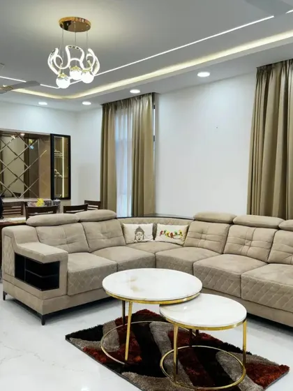 A spacious L-shaped sofa provides ample seating in this client's living room, complemented by nested coffee tables and a mirrored wall in the dining area to enhance the sense of space.