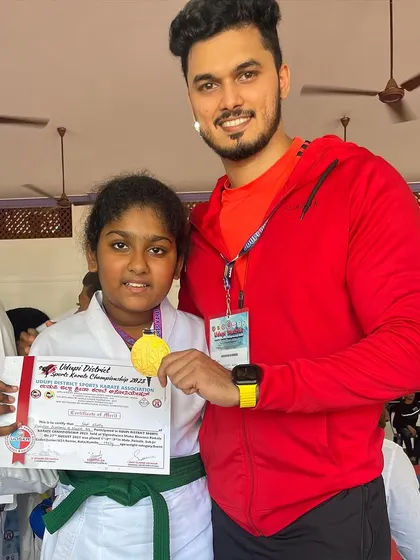 A green-belt student beaming with pride after winning her gold medal.
