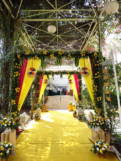 A vibrant yellow-themed entrance for a Haldi ceremony. The pathway is lined with colorful drapes and floral arrangements, creating a festive and cheerful welcome for guests.