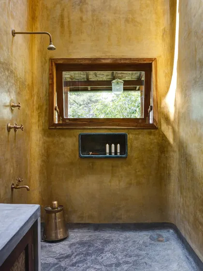 The bathroom of the Blue Room, finished in a warm yellow oxide plaster with brass fittings.