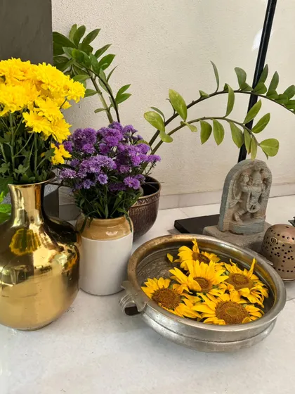 A simple yet elegant arrangement of sunflowers and other blooms in a mix of brass and ceramic vases, bringing warmth and color to a quiet corner.