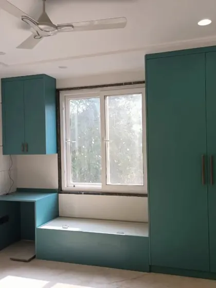 A delivered bedroom project featuring a wardrobe and study nook in a beautiful teal color. The design includes a window seat, making smart use of the available space.