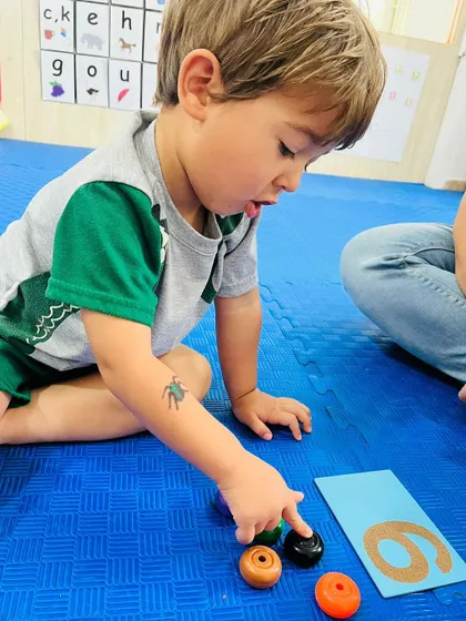 This student is carefully counting objects to match the number 6, demonstrating his developing numeracy skills.