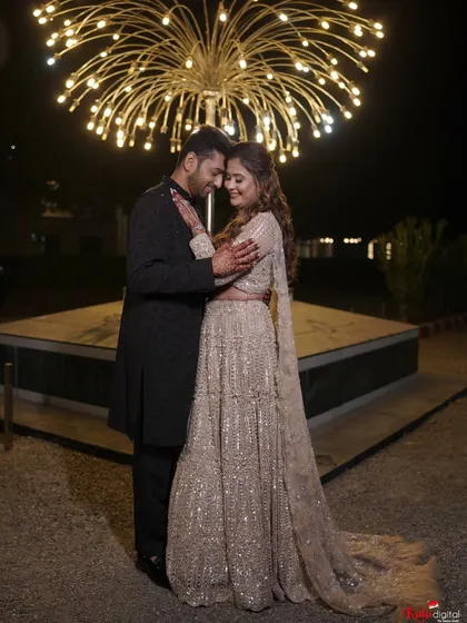 A wide shot of the couple under a beautiful light installation, the bride's sequined lehenga sparkling in the night.