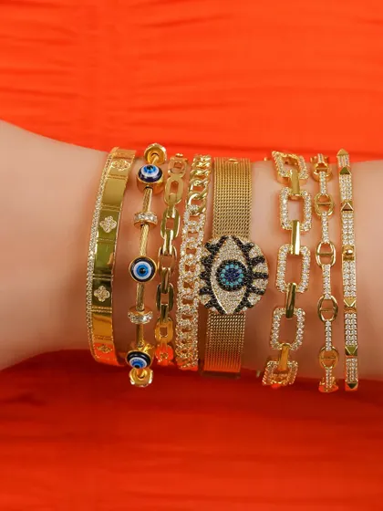 Summer ready with a bold arm stack. This close-up features my evil eye watch belt, studded link bracelets, and classic evil eye bangles.
