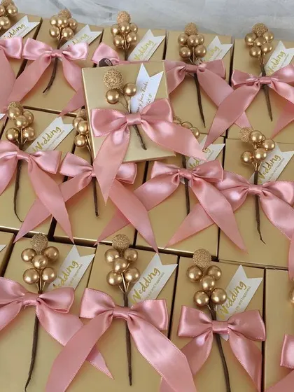 An elegant wedding return favor featuring a brass photo frame and scented candle, presented in a gold box with a decorative floral stick.