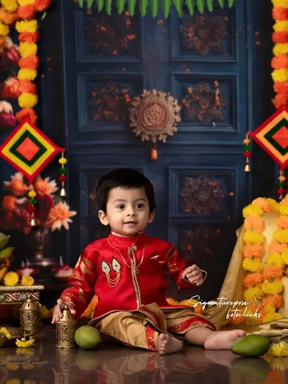 A full view of the traditional decor for a baby's festive photoshoot. The setup includes an antique-style door backdrop, marigold garlands, and brass items to create an authentic atmosphere.