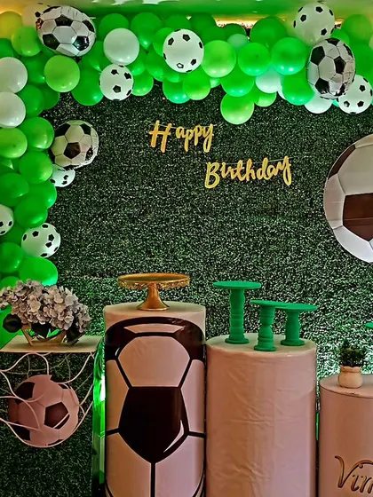 A football-themed party for Vimal's 11th birthday. We used a grass wall backdrop, a green balloon arch with football balloons, and themed pedestals to create a stadium-like feel for the celebration.