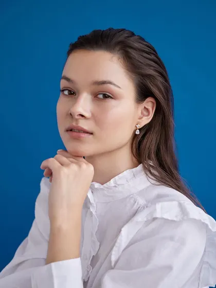 A fresh and bright jewelry shoot. The crisp white shirt and bold blue background make the delicate pearl earring stand out beautifully.