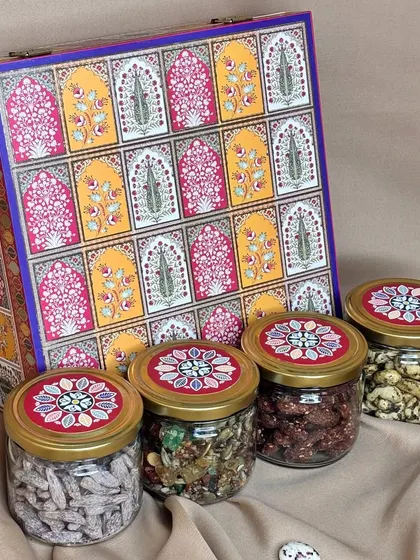 This four-jar dry fruit hamper features a beautiful box with a 'jharokha' window pattern. It’s filled with a premium selection of nuts and dried fruits.