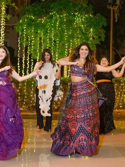 A group of friends dancing together under a canopy of fairy lights.
