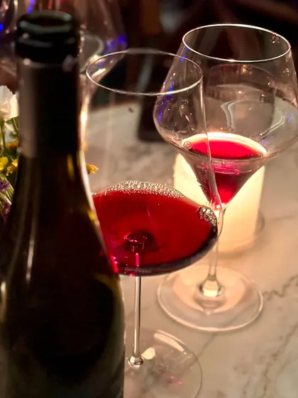 A close-up of a glass of rich red wine, poured during one of our tasting events. This image captures the sensory experience of our wine program, focusing on the color, aroma, and quality of the curated selections we offer.