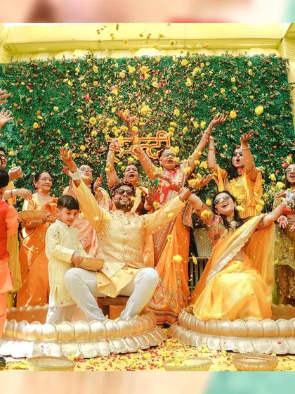 The whole family joins in the fun, showering the couple with petals during a vibrant Haldi ceremony. This image captures the essence of a big Indian family celebration.