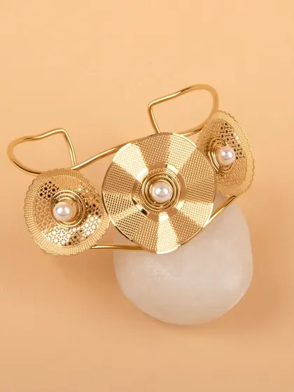 The gold floral cuff bracelet styled on a white stone for a natural, earthy feel.
