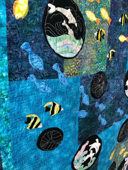 A detail shot of the sea quilt, showing the appliqué fish and Sashiko-stitched waves.