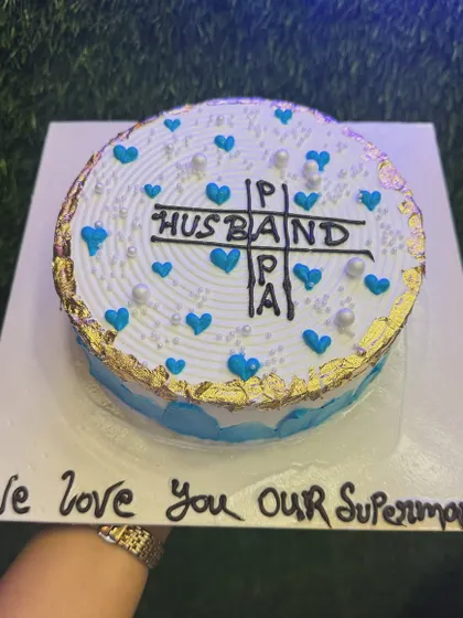 A heartfelt cake for a husband and papa, calling him "Our Superman." The design is simple yet full of love, with blue hearts and a touching message that comes straight from the heart.