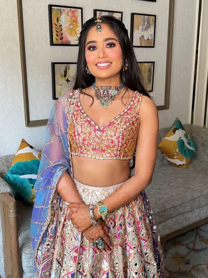 The bride looking joyful and radiant, her playful hairstyle perfect for a daytime Mehendi party at a destination wedding.