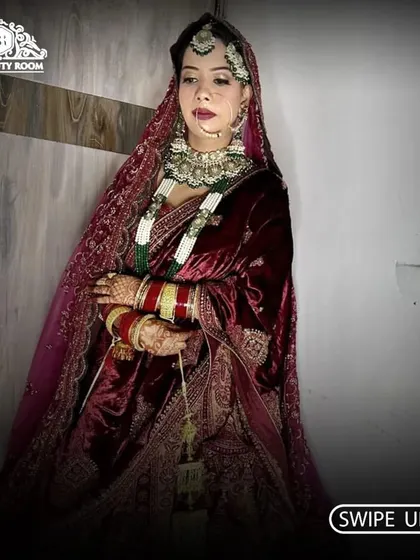 A full view of a bride in a rich, velvet maroon lehenga. The makeup was designed to be regal and dramatic, matching the luxurious feel of her outfit.