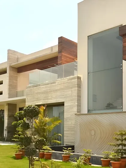 This view highlights the home's integration with its environment. The use of natural stone, wood cladding, and large glass panels creates a dialogue between the structure and the manicured landscape surrounding it.