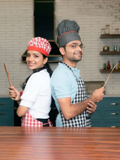 Another shot from our popular chef-themed pre-wedding shoot. The couple stands back-to-back with wooden spoons, ready for a cook-off, showcasing a creative and lighthearted approach to engagement photos.