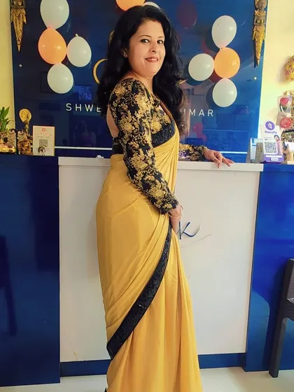 Standing in my studio in a mustard yellow saree with a contrasting black sequin border and a full-sleeve embroidered blouse. This is my creative space where I bring fashion ideas to life.