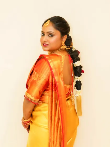 A classic South Indian bridal look from the side. The focus is on the traditional braided hairstyle with flowers, bold eyes, and a flawless complexion that radiates elegance.