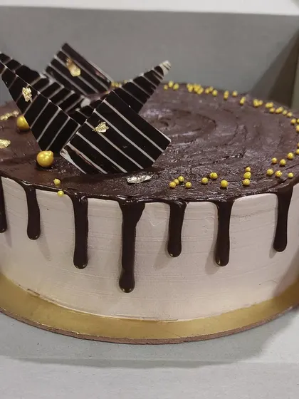A classic chocolate drip cake design with a smooth finish. It's topped with modern chocolate fan decorations and a sprinkle of gold for a touch of class.